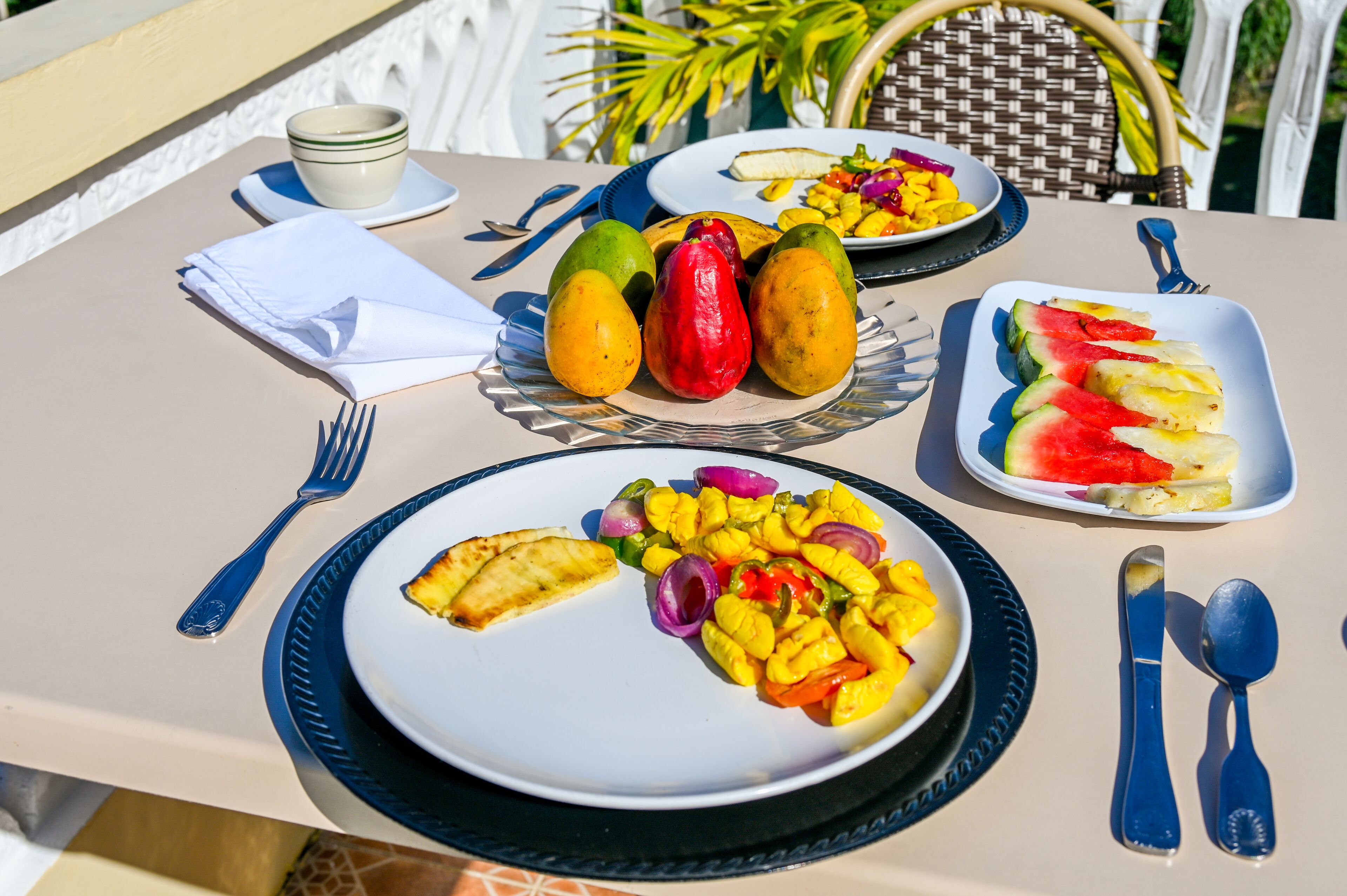A table set with plates of fruit, a bowl of salad, and cutlery.