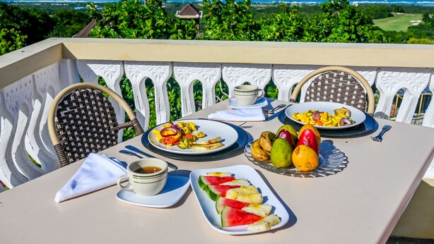 A table set with plates of food, a cup of coffee, and a view of the ocean. - Takuma Boutique Hotel Rooms & Suites Jamaica  (Montego Bay)