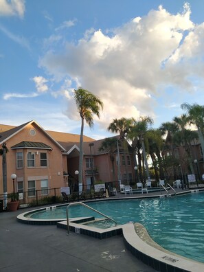 A swimming pool area with a pool, lounge chairs, and palm trees. - Relax & Recharge (Kissimmee)