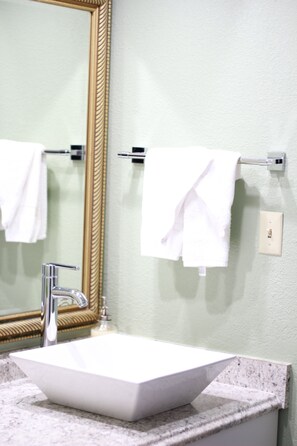 Ein Badezimmer mit einem weißen Waschbecken, einem großen Spiegel und zwei Handtüchern an Handtuchhaltern.