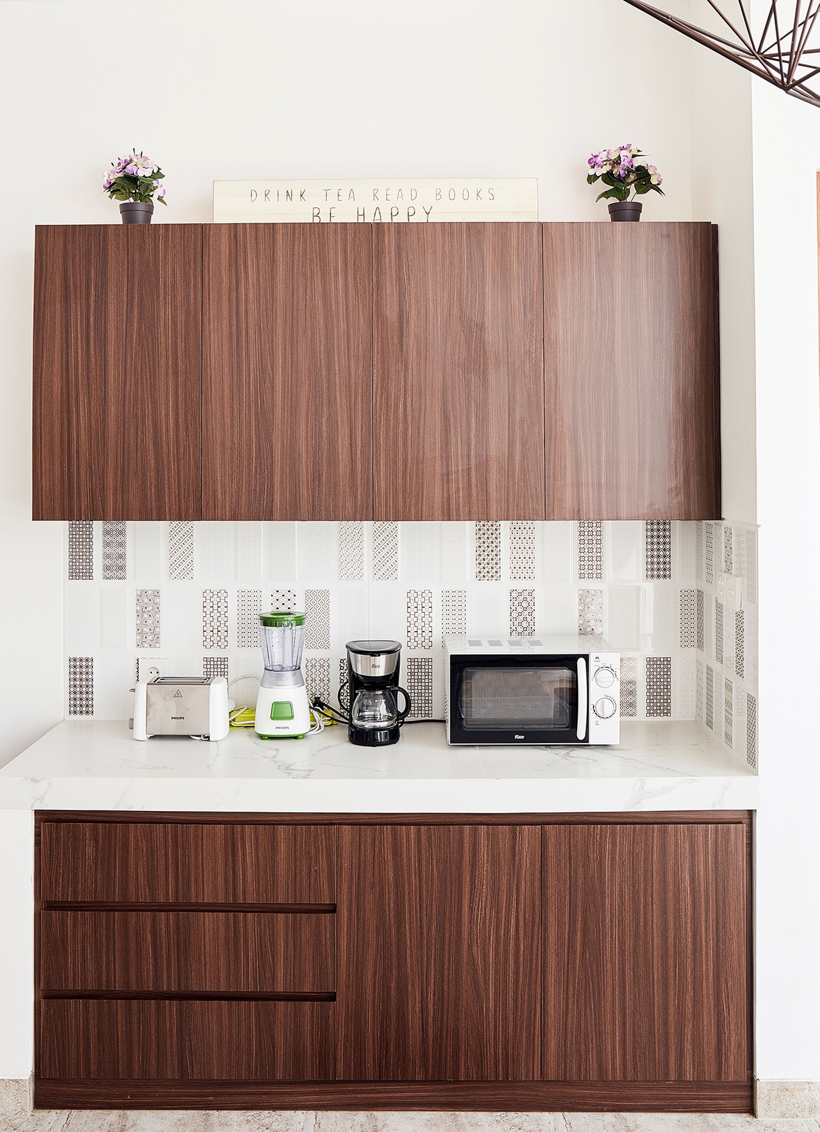 A kitchen with a wooden cabinet, a toaster, a blender, a coffee maker, and a microwave.