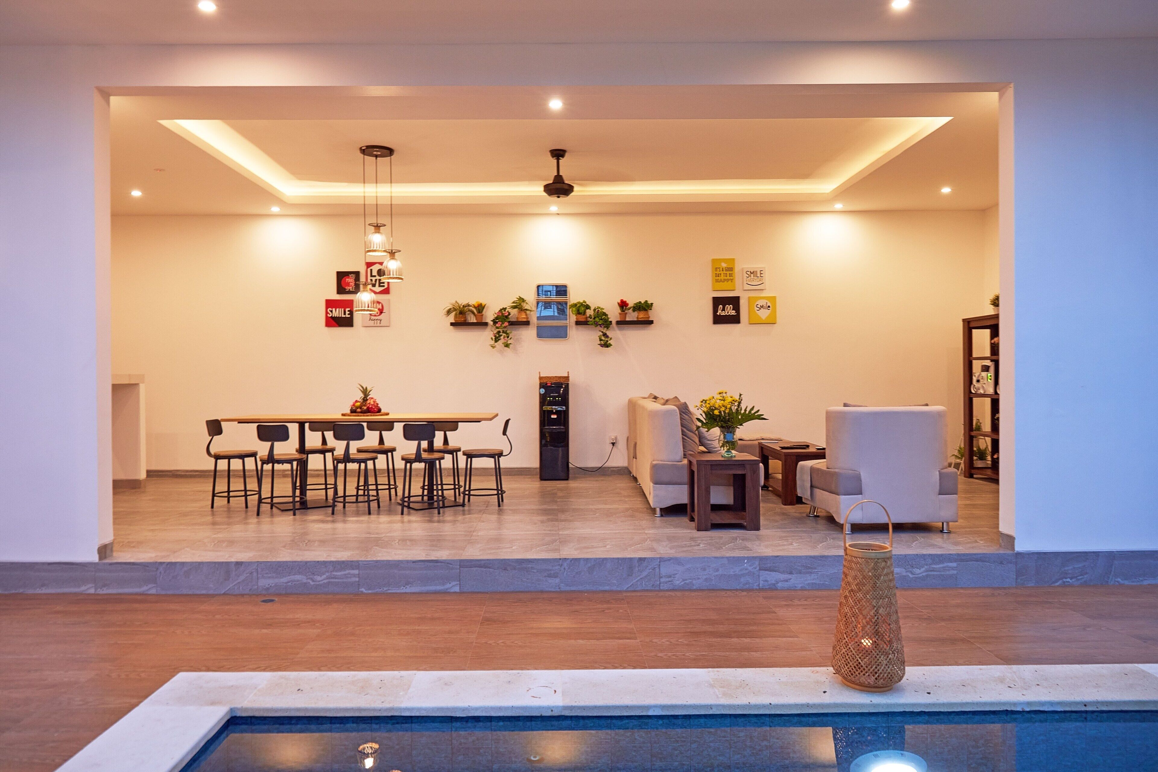 A modern living room with a dining area, a sofa, a coffee table, and a small pool area.