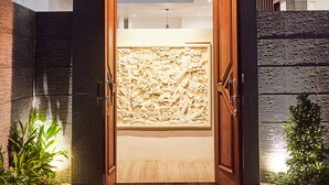 Une entrée moderne avec une porte en bois, un décor en relief et un petit espace jardin.