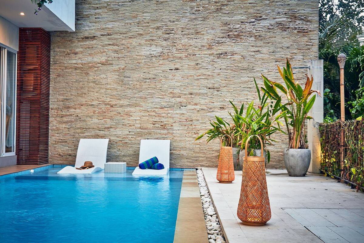 A swimming pool with lounge chairs and potted plants.