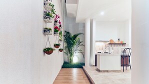 Un couloir au plancher de bois mène à une cuisine dotée d’un comptoir blanc et d’un évier.