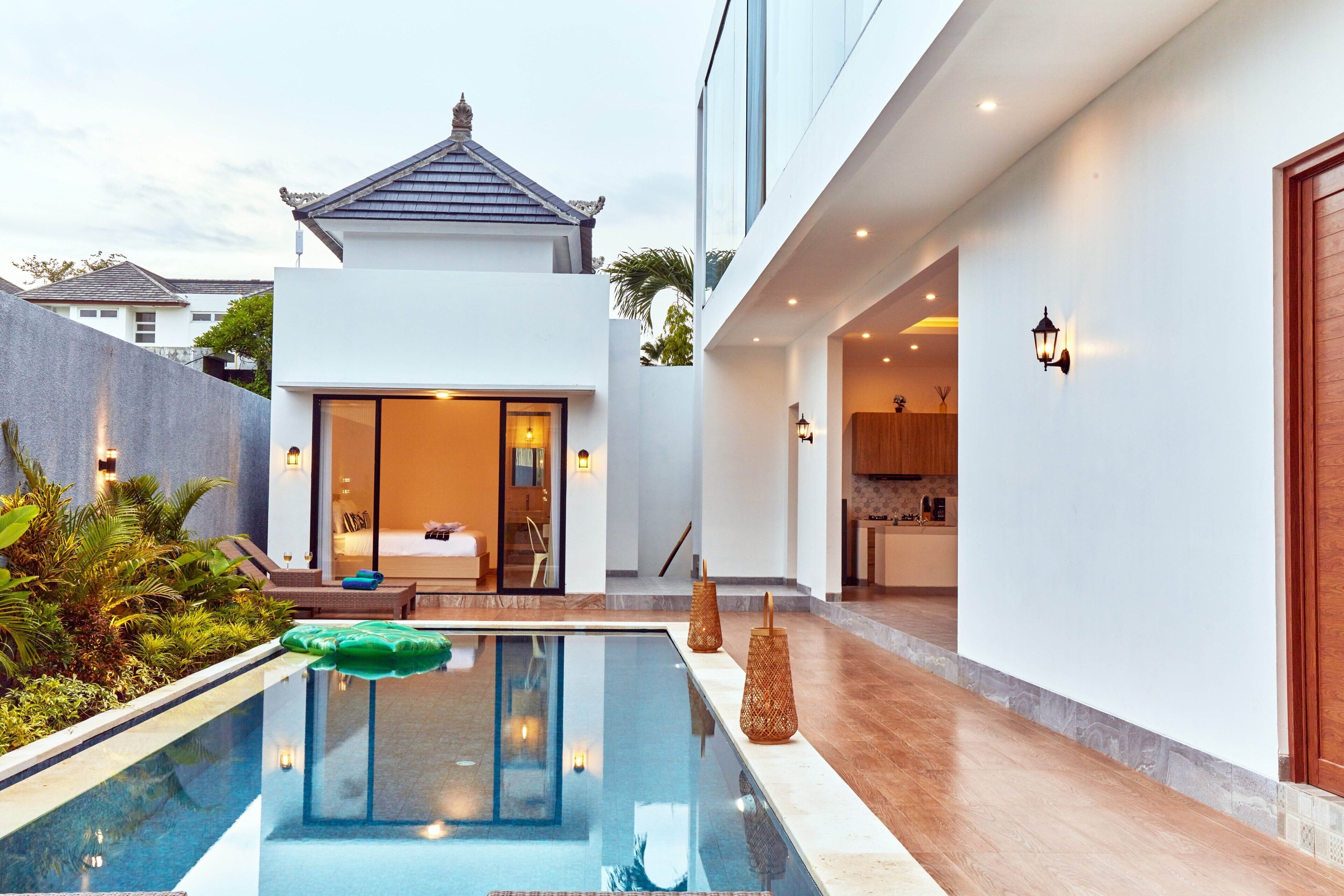 A modern pool area with a glass barrier, a lounge chair, and a small table.