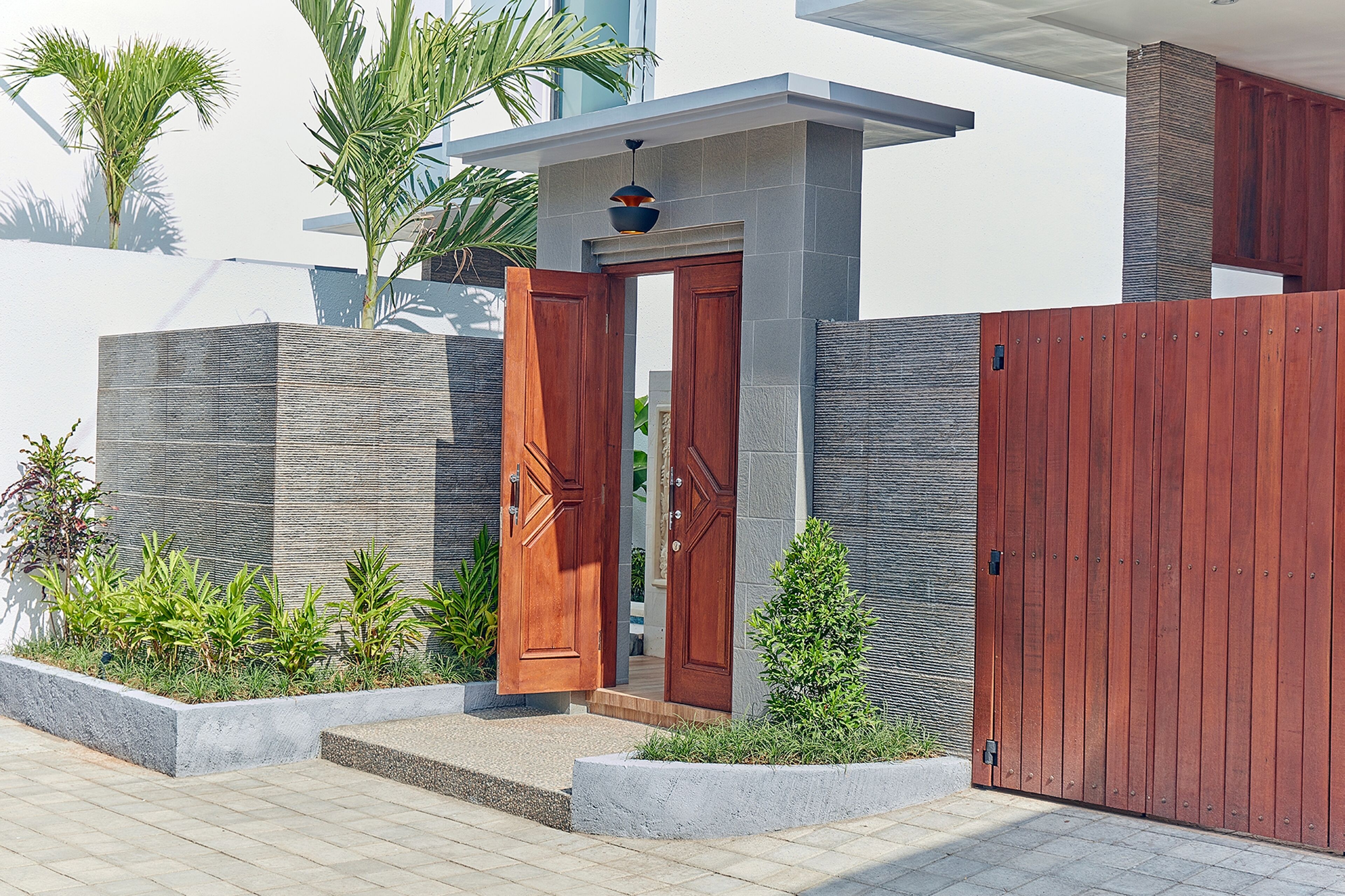 A modern house with a wooden door, a concrete wall, and a wooden fence.