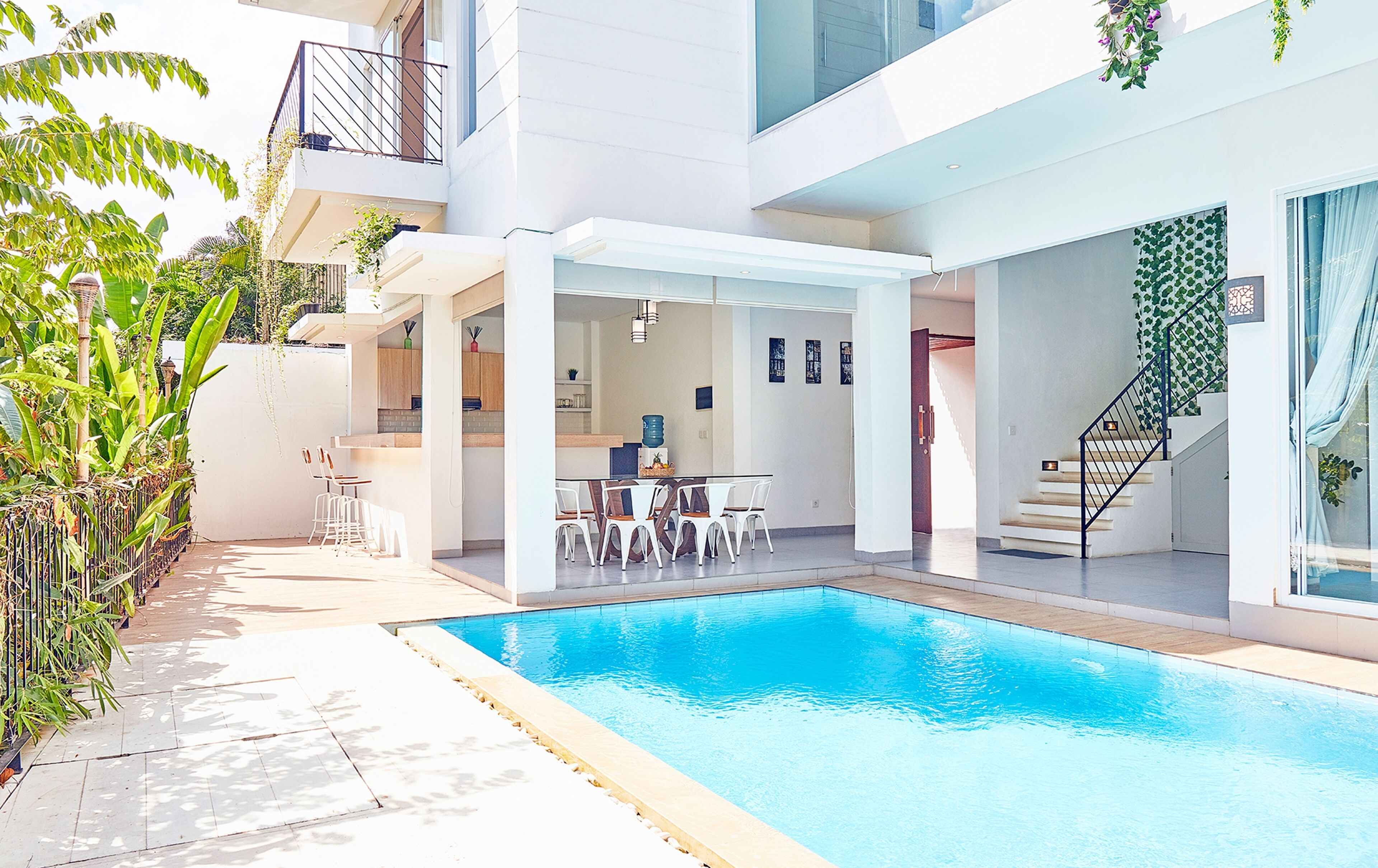 Et moderne poolområde med spiseplads og en trappe til en etage over.
