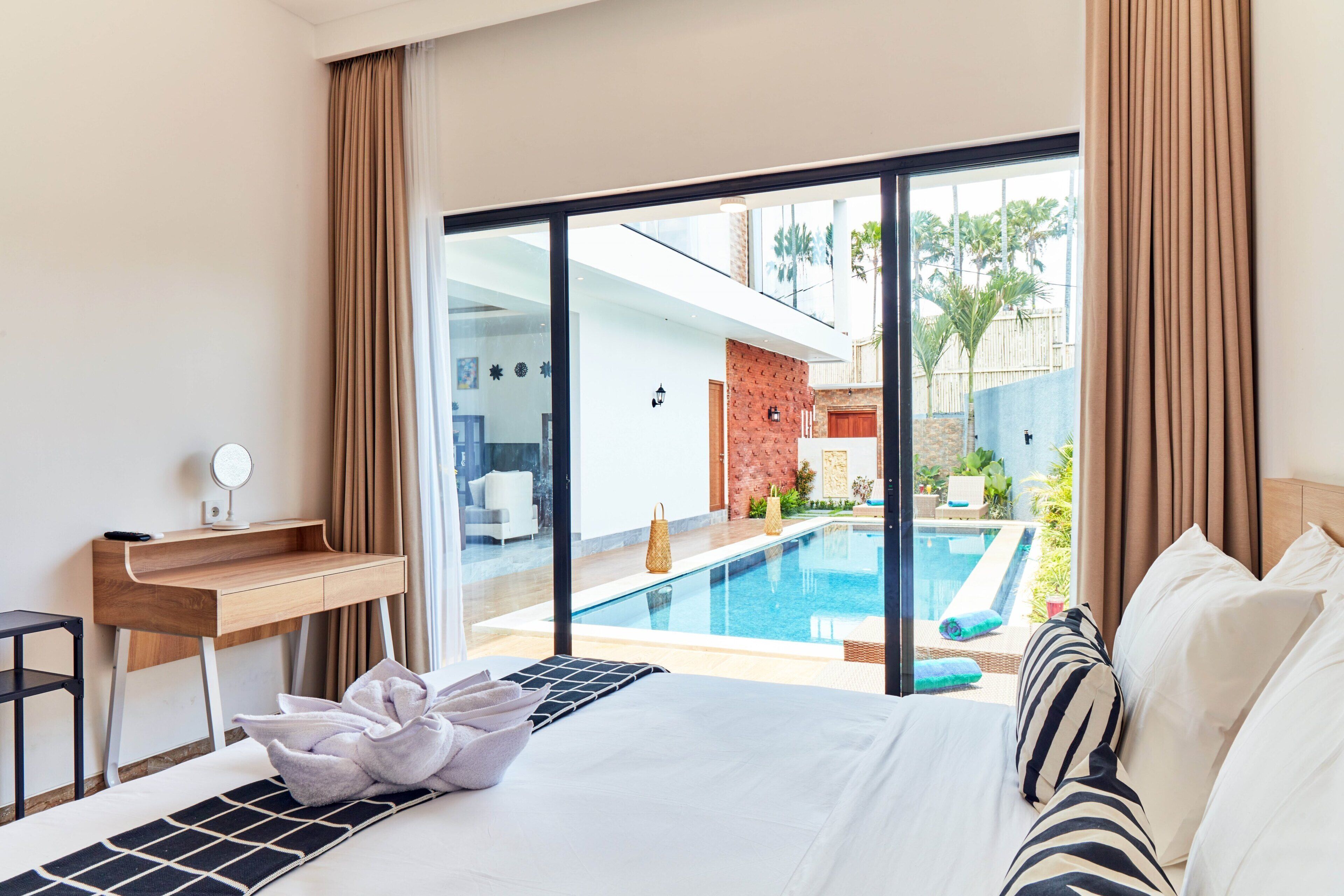 Una habitación de hotel con una cama, un escritorio y vistas a una piscina.