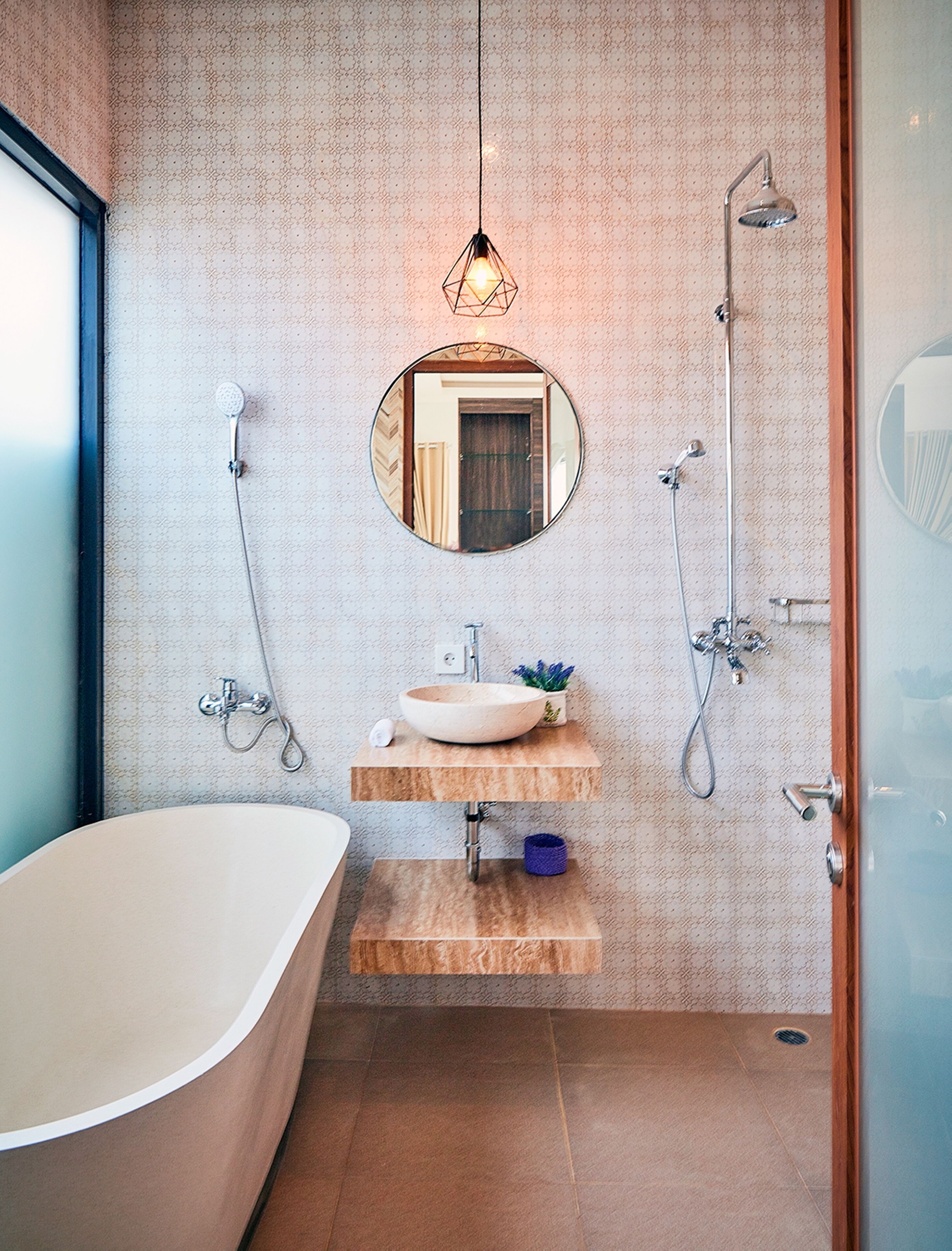 A modern bathroom with a freestanding bathtub, a round mirror, a wooden vanity with a bowl sink, and a shower with a handheld showerhead.