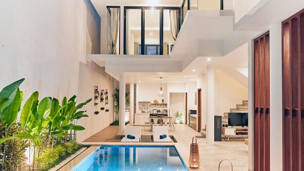 Un espace piscine intérieur moderne, avec une cuisine et un coin repas en arrière-plan.
