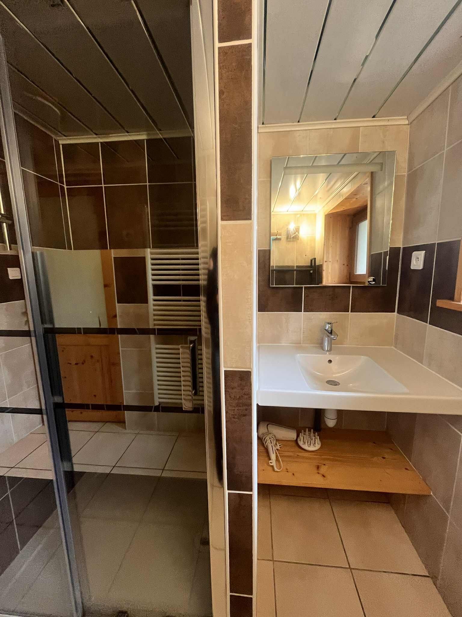 A bathroom with a white sink, mirror, and tiled walls.