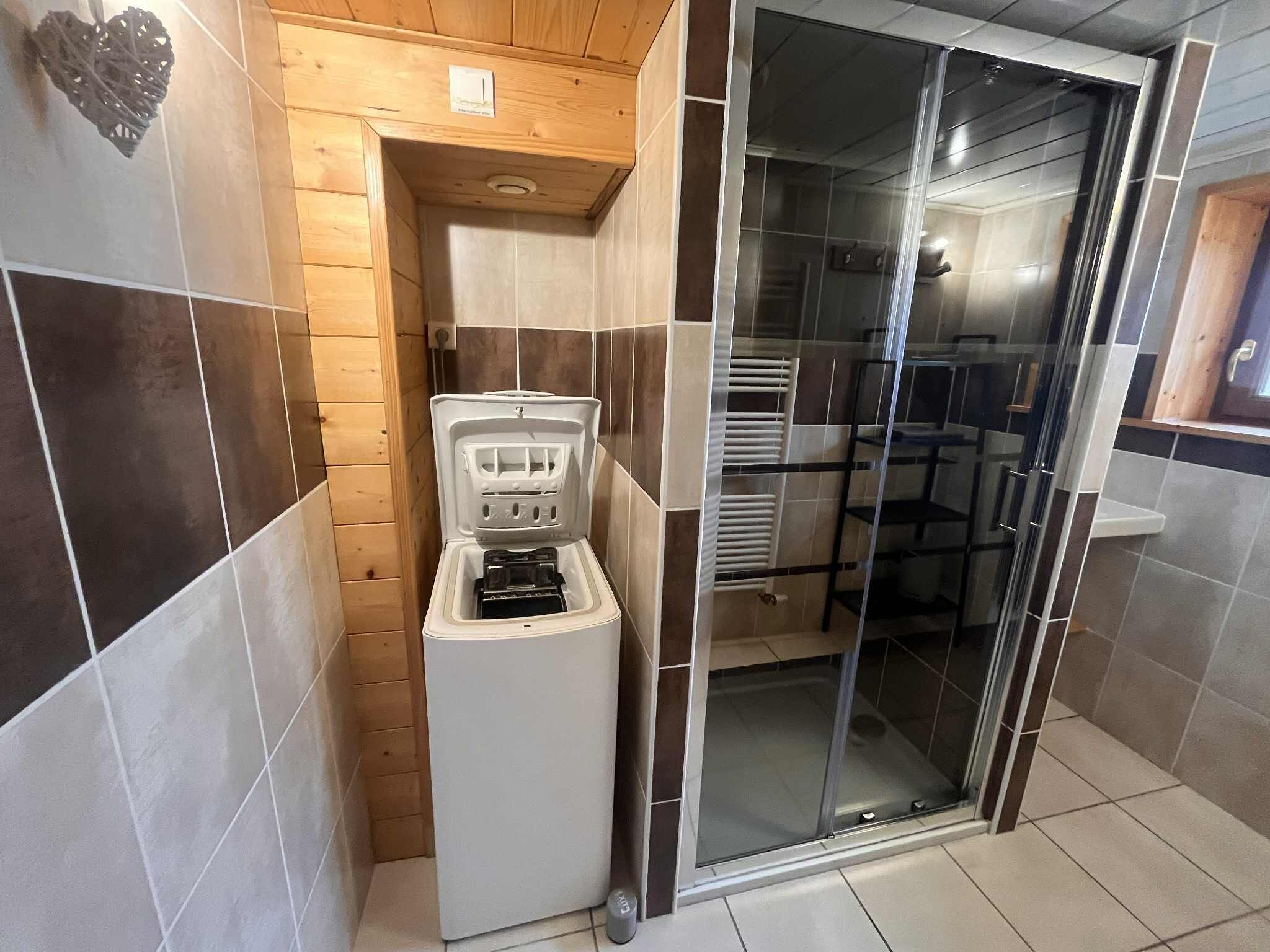 A compact bathroom with a shower enclosure, a toilet, and a small storage unit.
