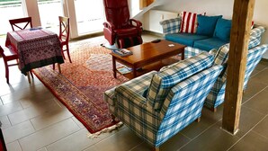 A living room with a sofa, armchair, coffee table, and a rug. - Deosai (Kelkheim)