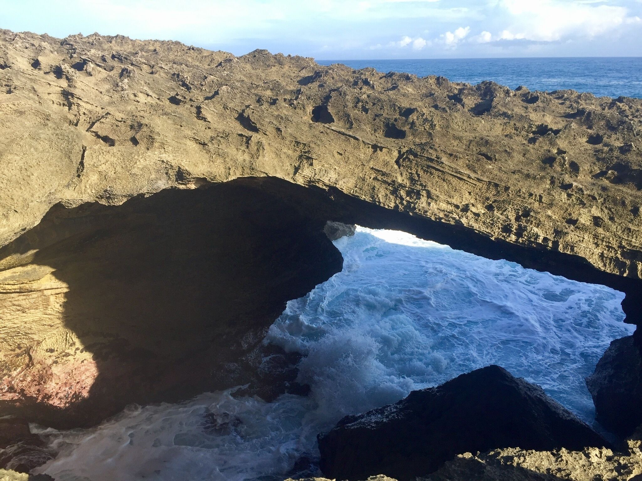 Una costa rocciosa con un arco naturale e onde che si infrangono.