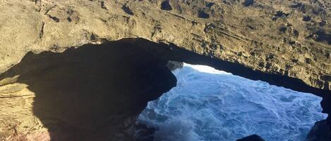 Una costa rocciosa con un arco naturale e onde che si infrangono.