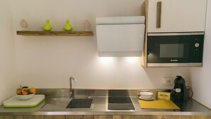 A modern kitchen with a built-in microwave, a coffee machine, and a scale. - Dione monolocale quiet and confortable (Syracuse)