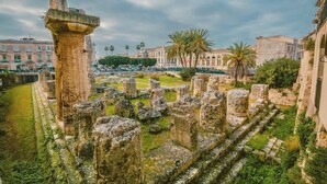 Ancient ruins with stone columns and steps, surrounded by greenery and historic buildings. - Dione monolocale quiet and confortable (Syracuse)
