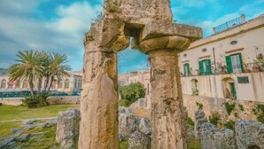 Ancient stone ruins with a view of traditional buildings in the background. - Dione monolocale quiet and confortable (Syracuse)