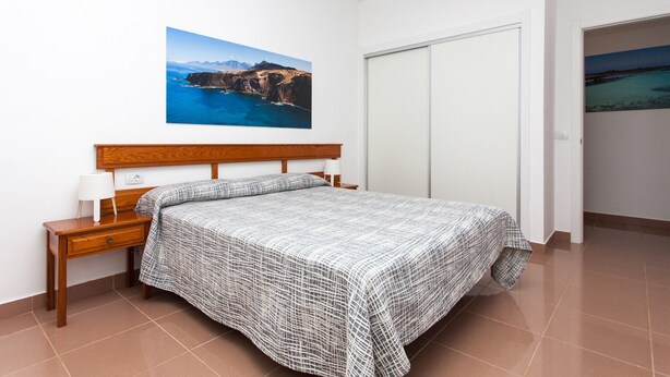 Ein Schlafzimmer mit Bett, Nachttisch und einem Gemälde einer Küstenlandschaft.