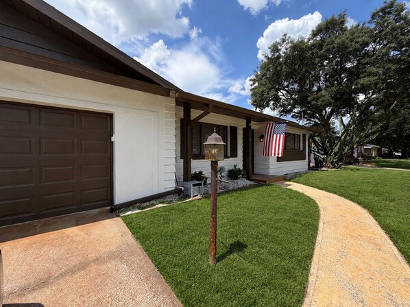 A residential house with a garage, a front porch, and a well-maintained lawn.
