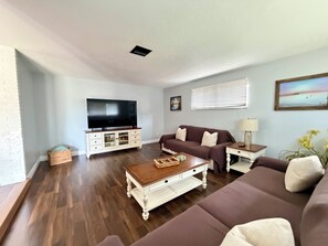 A living room with a television, sofa, coffee table, and a window with blinds. - The Oasis Private Pool Home + Best Launch Views! No cleaning fee. (Titusville)