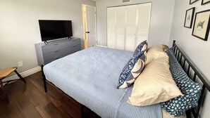 A bedroom with a bed, a television on a dresser, a ceiling fan, and a door. - The Oasis Private Pool Home + Best Launch Views! No cleaning fee. (Titusville)