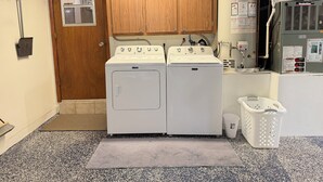 A laundry room with two Maytag washers and dryers, a water heater, and a utility room door. - The Oasis Private Pool Home + Best Launch Views! No cleaning fee. (Titusville)