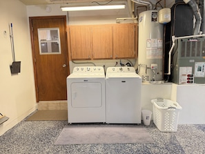 A laundry room with two Maytag washers and dryers, a water heater, and a utility room door.