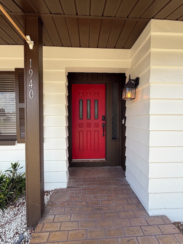 A red door with a mailbox, a number '1940' sign, and a lantern on the porch.