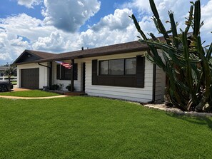 Une maison de plain-pied avec un garage, un porche à l’avant et une pelouse bien entretenue.