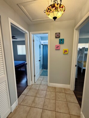 Un couloir avec un ventilateur de plafond, une porte donnant sur une chambre et un escalier.