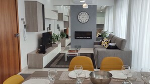 Ett modernt vardagsrum med en soffa, ett matbord med plats för fyra personer och en stor väggklocka.