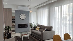 Ett modernt vardagsrum med en grå soffa, en platt-TV och en matplats med ett bord och stolar.