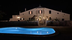 Un grande edificio bianco con una piscina di fronte.