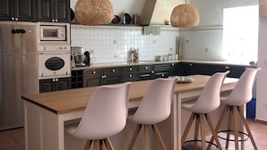 Una cucina moderna con isola centrale, elettrodomestici integrati e illuminazione a sospensione.