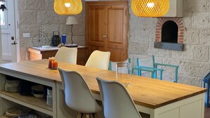 Una cucina con un'isola in legno, due lampade a sospensione, un forno a mattoni e una bicicletta decorativa appesa al muro.