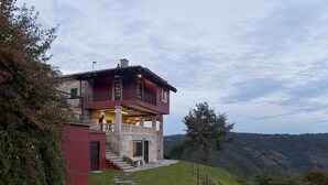 A two-story house with a balcony, stone steps, and a stone wall.