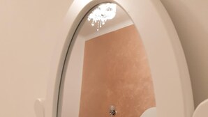 Un dormitorio con una cama, una mesita de noche y un espejo.
