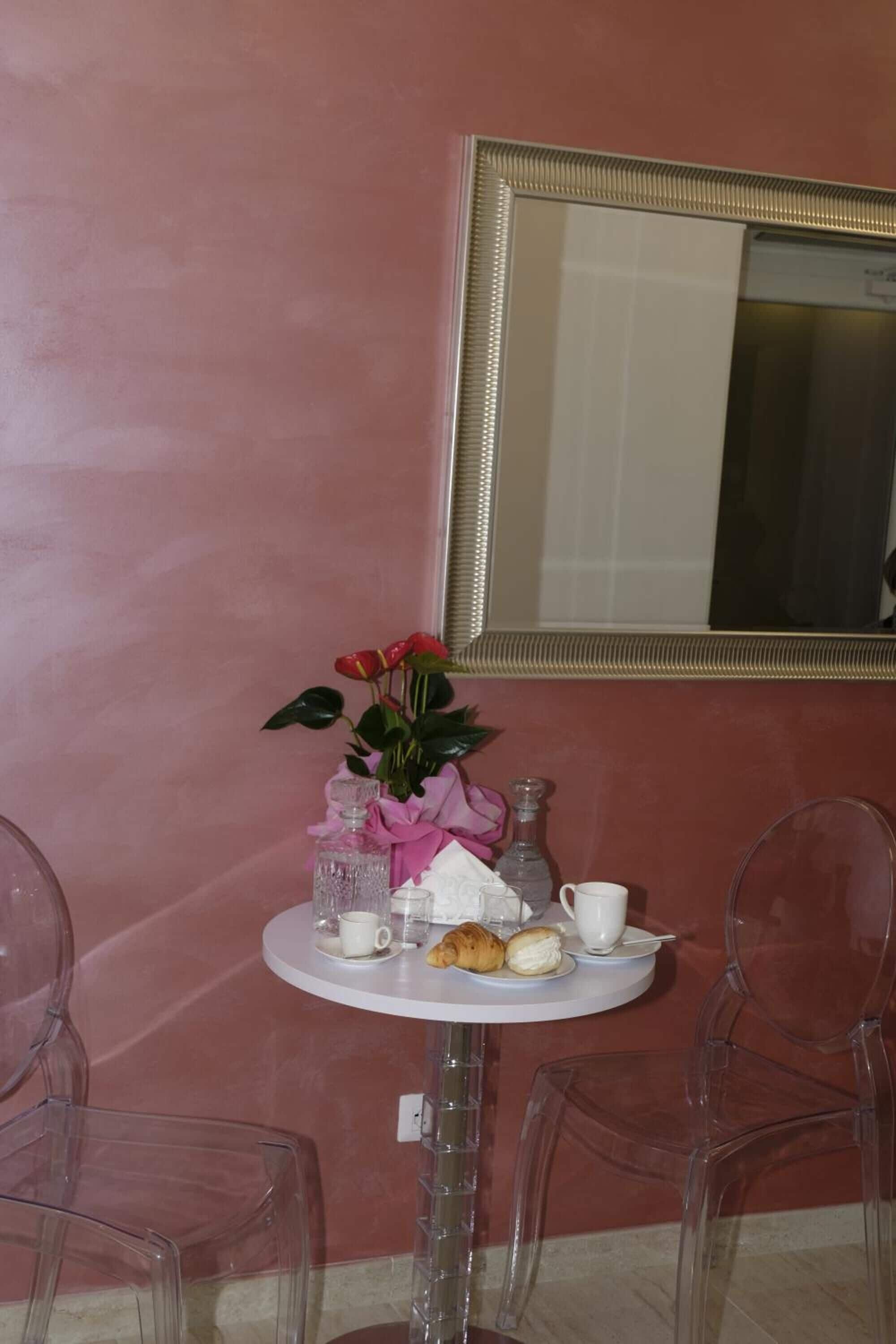A small round table with a white cup, a teapot, a sugar bowl, and pastries.