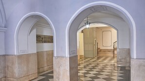 Un pasillo con suelo a cuadros, paredes blancas y arcos.