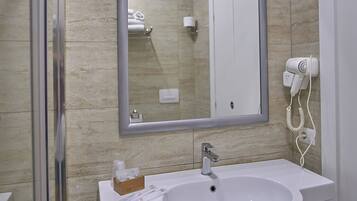 A modern bathroom with a large mirror, a sink, and a hairdryer on the wall.