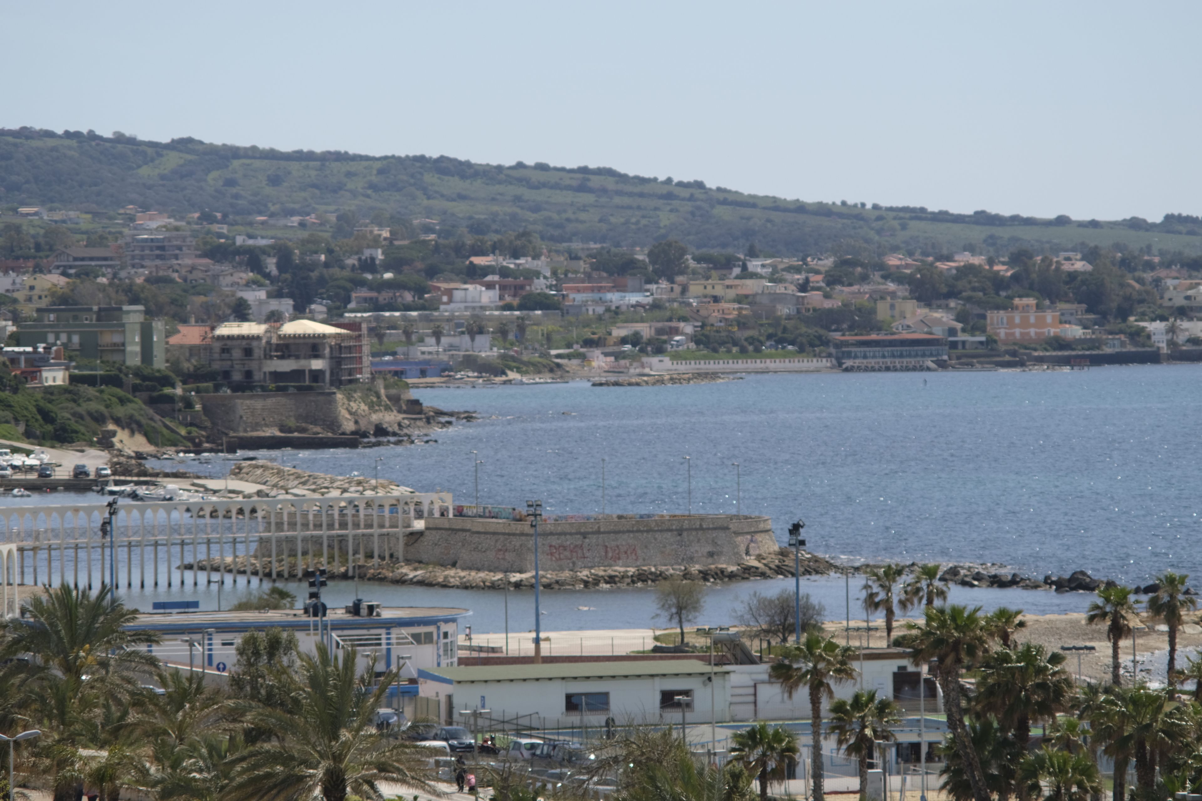 Un pueblo costero con un puerto deportivo, edificios y palmeras.