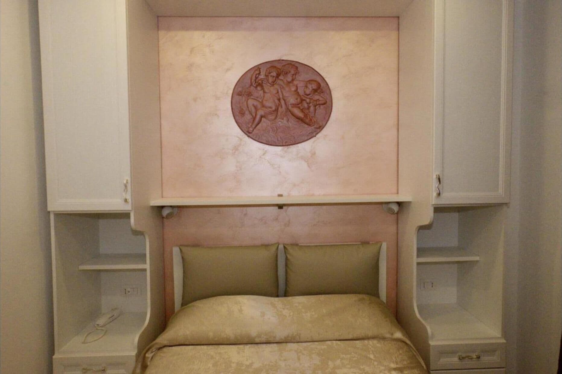 A bedroom with a bed, a circular decorative panel above the bed, and built-in shelving on either side.