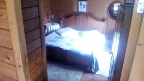 A wooden cabin bedroom with a bed, a small table, and a picture on the wall. - My holiday refuge in the Northeast of Mallorca (Font de Sa Cala)