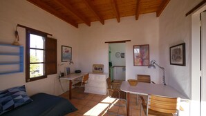 Une pièce de taille modeste comprenant un lit, un bureau, une chaise, une table à manger et un coin cuisine.