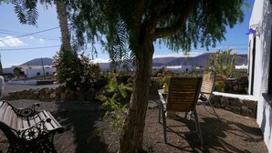 Une terrasse avec un banc en bois, une chaise en métal et une table sur laquelle est posée une lanterne.