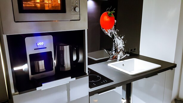 A modern kitchen with a built-in microwave, coffee maker, and sink.