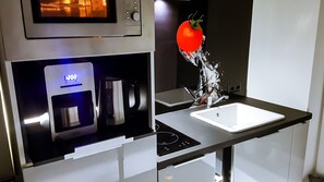 Een moderne keuken met een ingebouwde magnetron, koffiezetapparaat en spoelbak.