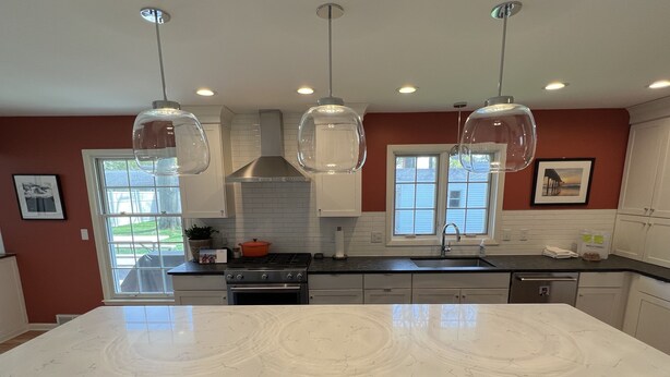A modern kitchen with a large island, pendant lights, and a view to the outdoors. - Fantastic 4-Bedroom Family Home - Short Walk to Michigan Stadium (Ann Arbor)